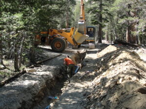 a man Laying new pipe and an excavator