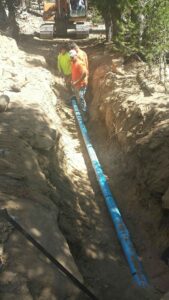 view of a blue pipe being installed by people