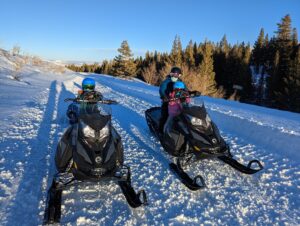 two people are riding a snow bike