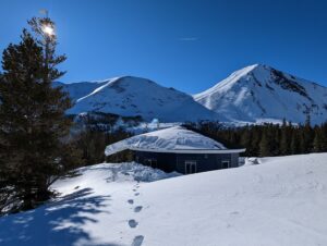 snow covered mountains, trees, and a house