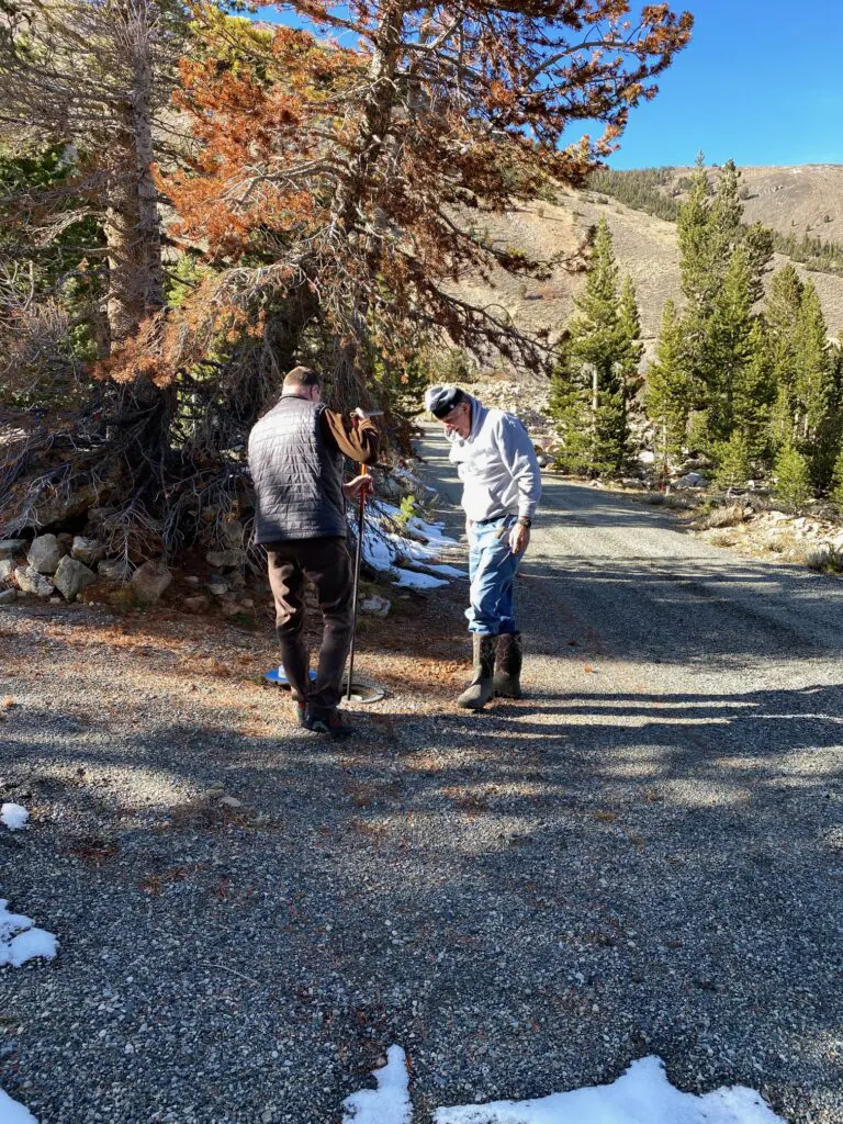 two men closing water valve with tool